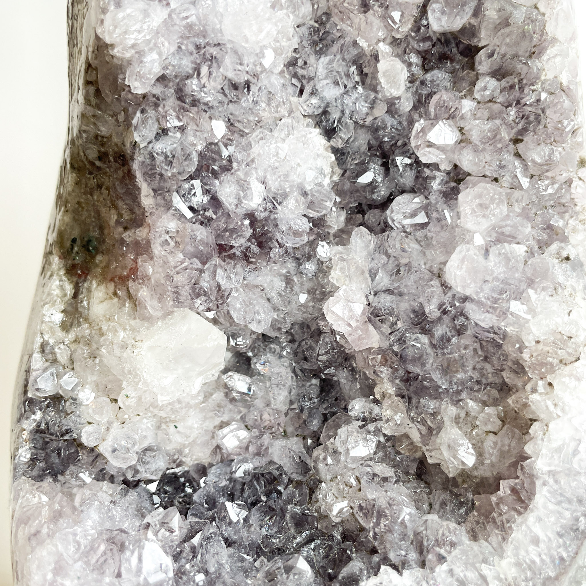 A close-up view of an agate geode, showcasing a variety of sparkling crystals ranging from translucent to shades of grey and white.