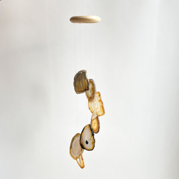 A mobile hanging from the ceiling with several slices of agate stone suspended on thin strings against a plain white background.