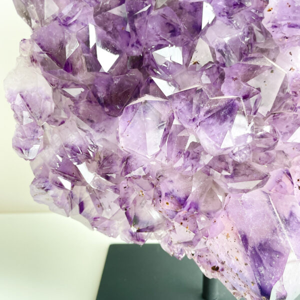 A close-up photograph of a large amethyst crystal cluster with multiple translucent purple points.
