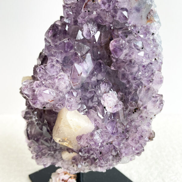 A close-up of an amethyst geode showing a cluster of purple crystals with some white quartz formations.