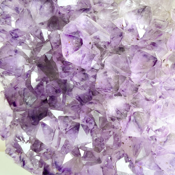 Close-up photograph of a cluster of purple amethyst crystals with sharp geometric shapes and varying clarity.