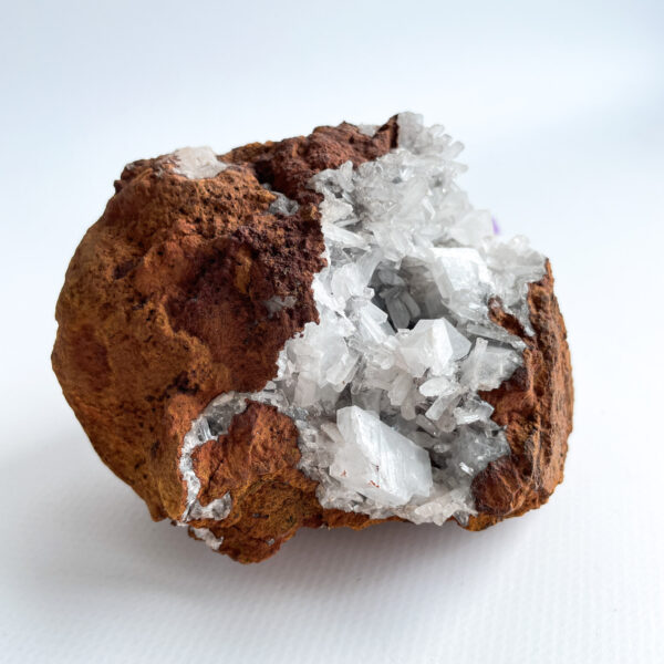 A geode with clear quartz crystals inside, set against a white background.